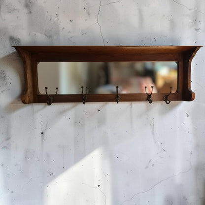Antique oak wall mounted coat rack with mirror shelf and cast iron hooks on stone wall