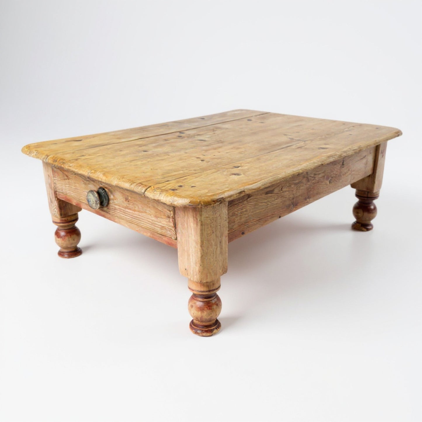 Front view of antique pine coffee table showing plank top and turned legs