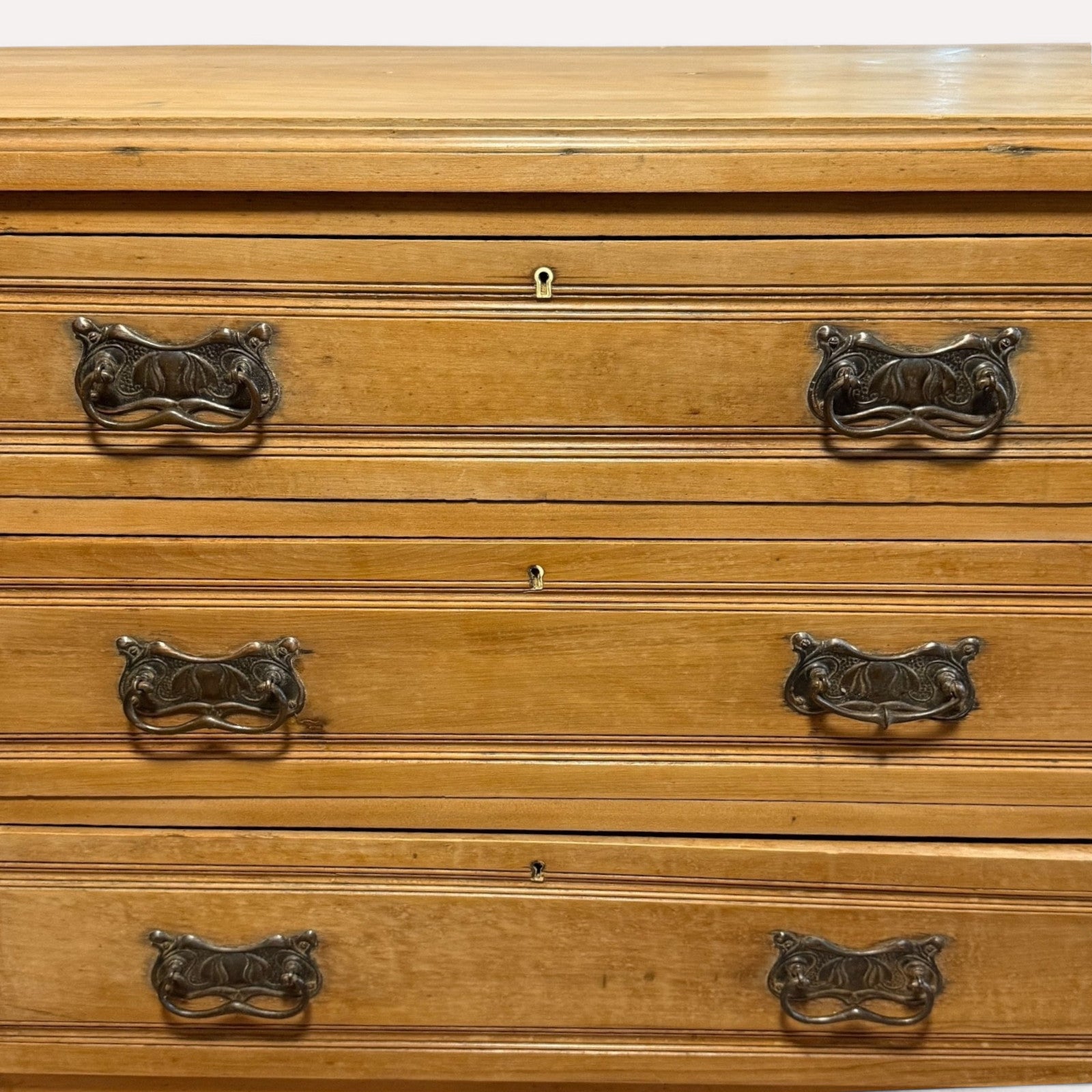 Close-up of ornate brass drawer handles on antique pine chest