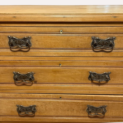 Close-up of ornate brass drawer handles on antique pine chest