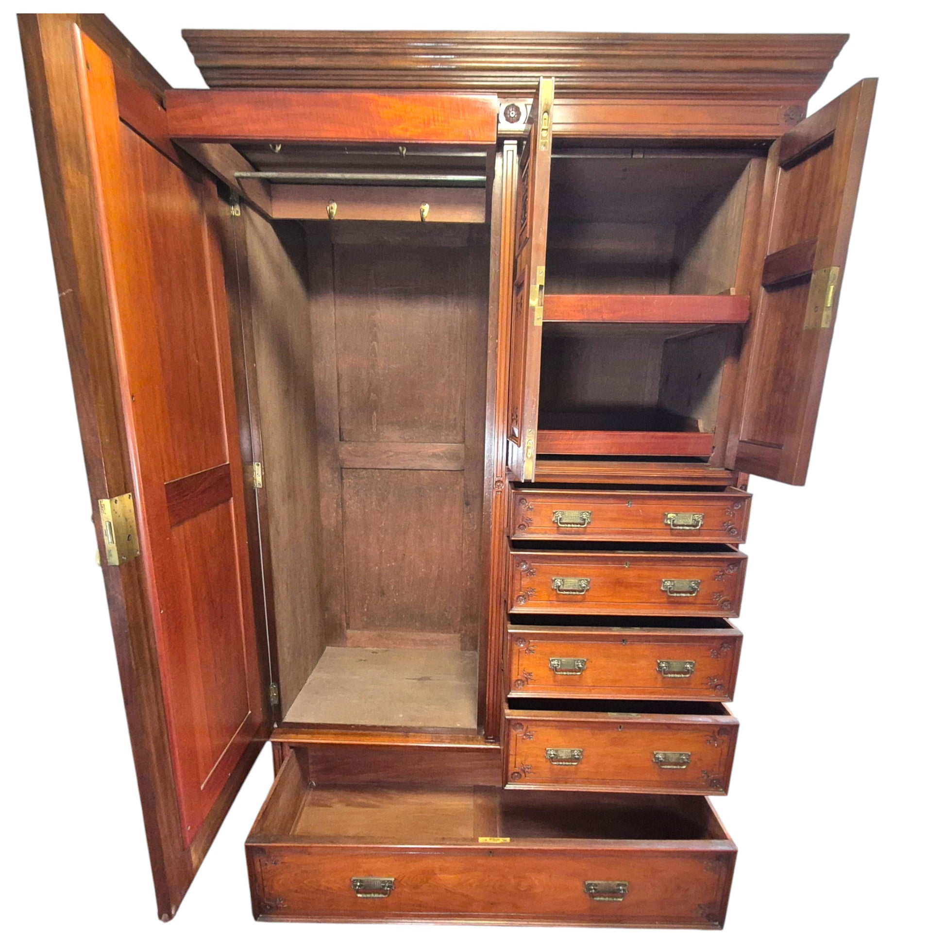 Close up of Victorian walnut wardrobe drawers with ornate brass handles and carved decorative detail