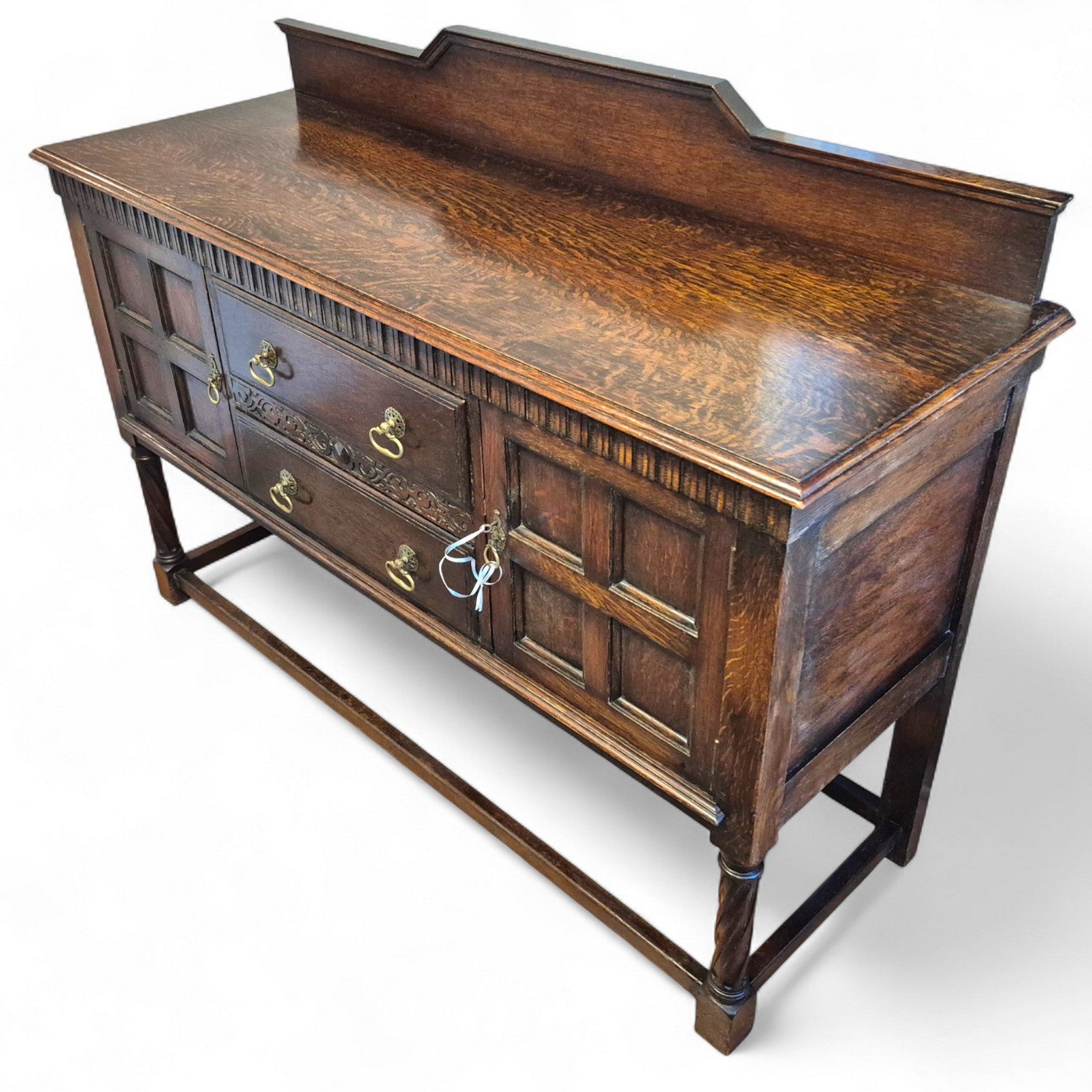 Side angle of Waring & Gillows oak cabinet with turned supports and raised back