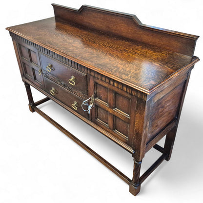 Side angle of Waring & Gillows oak cabinet with turned supports and raised back