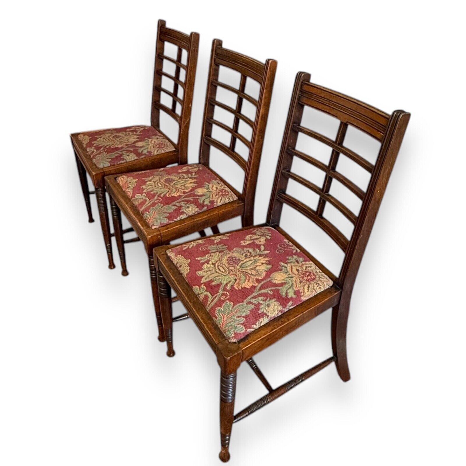 Angled view of Victorian mahogany ladderback chairs showing warm wood tone and classic Arts & Crafts design