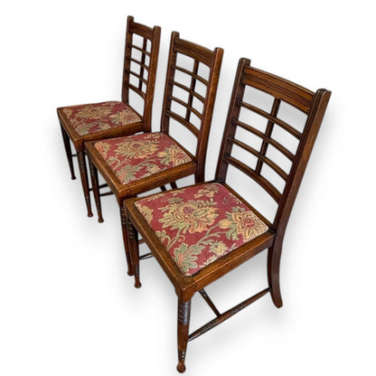 Angled view of Victorian mahogany ladderback chairs showing warm wood tone and classic Arts & Crafts design