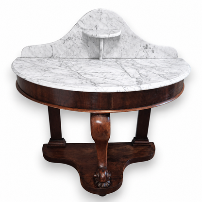 Front view of a Victorian mahogany washstand featuring a curved marble top and carved central support.