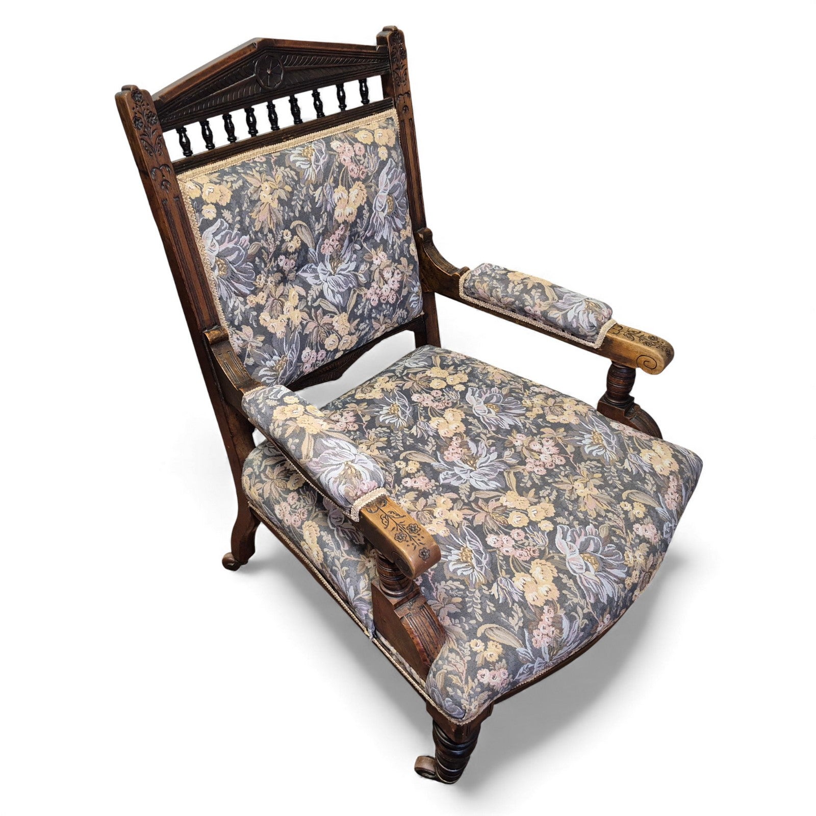 Angled view of Victorian oak nursing chair showing turned arm supports and castors