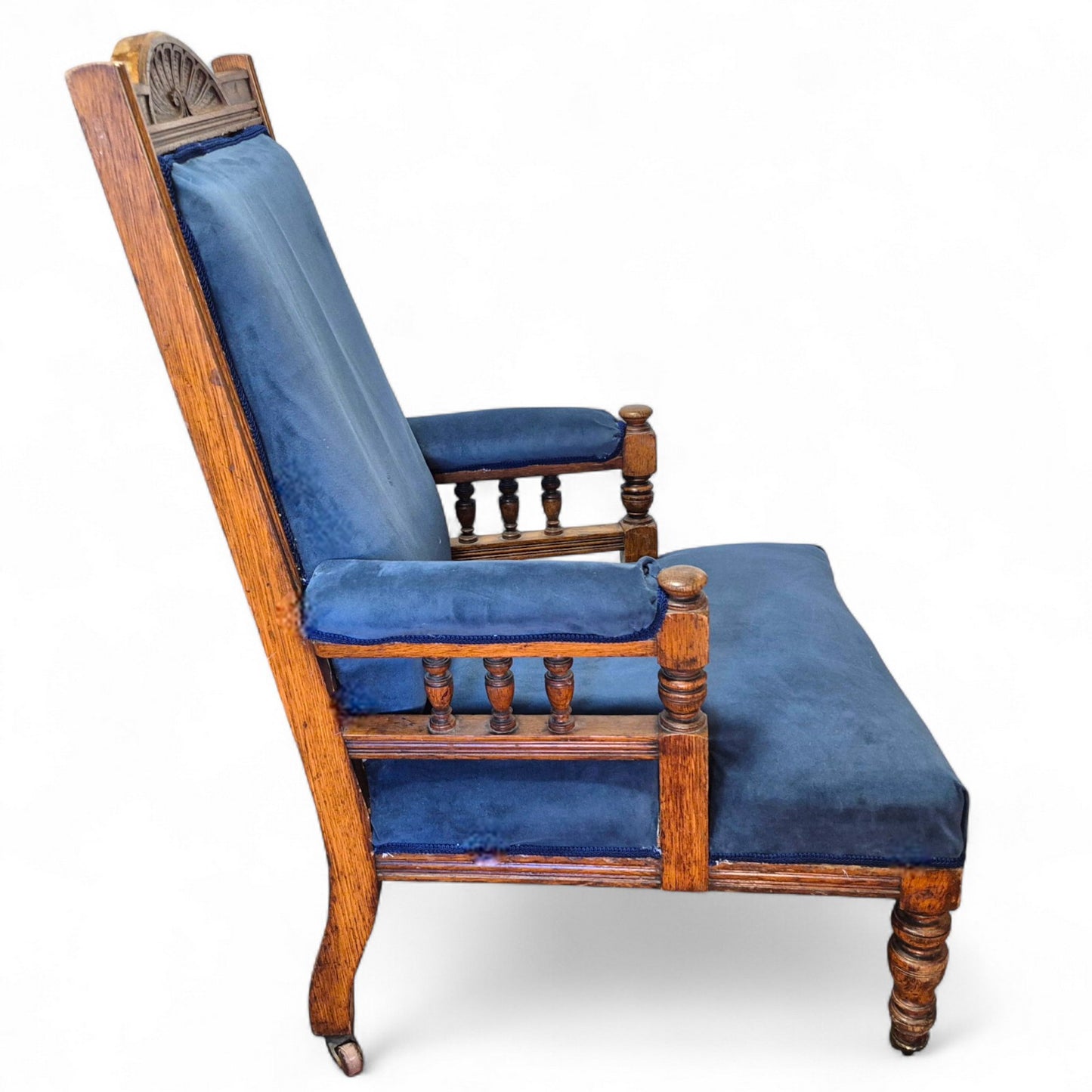 Side view of Victorian oak nursing chair with castor legs and upholstered seat