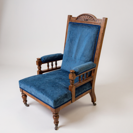 Antique Victorian oak nursing chair with carved backrest, spindle arms and blue upholstery