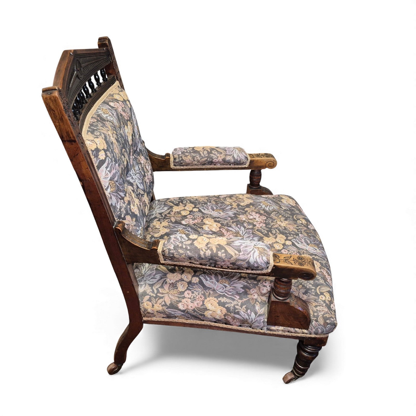 Side view of Victorian oak nursing chair showing turned arm supports and castors