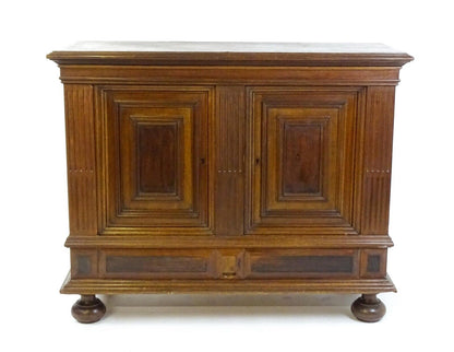 Front view of antique walnut cupboard with moulded top and storage drawer